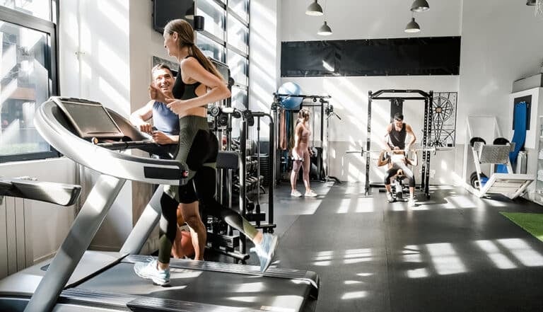 Athletic woman running on treadmill in contemporary gym