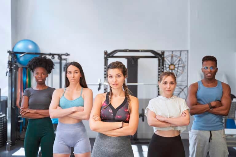 Confident female trainer standing in front of team at the gym