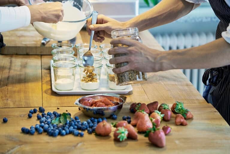 Two chefs preparing berry desserts, mid section