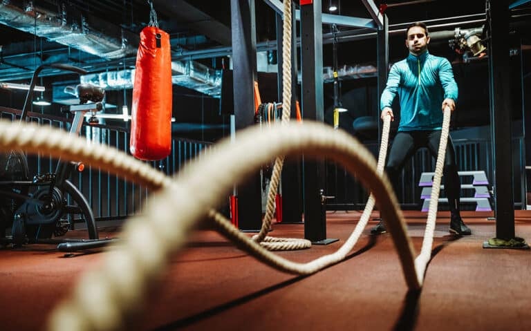 Fitness man working out with battle ropes at gym