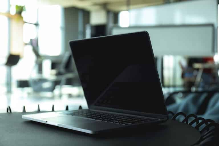 Laptop on black table in coworking space, close up