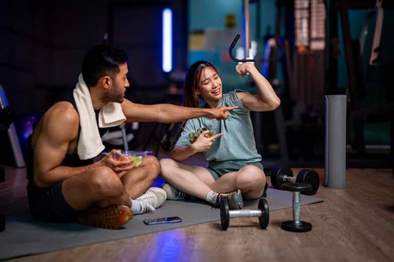 Two men and women are eating a vegetable salad together after ex
