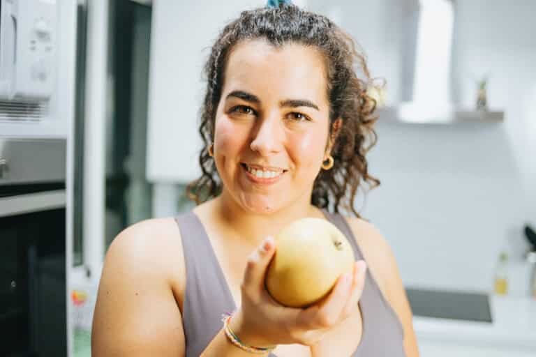Young plus size woman playing with healthy food at the kitchen,