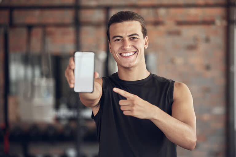 Happy man pointing to his phone in the gym Happy man pointing to his phone in the gym
