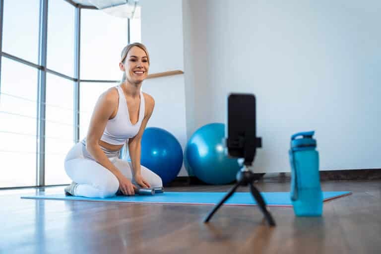 Joyful girl sits in front of phone camera and records online workout
