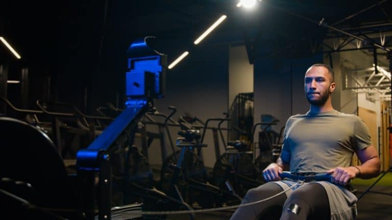 Powerful heavy weight machine sportive equipment workout in sport gym sports club strong athletic African American man athlete sportsman doing push down sitting horizontal pull block back exercise