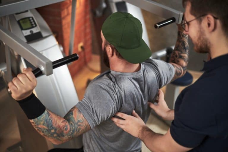 Training in Gym with Personal Trainer Spotting Client