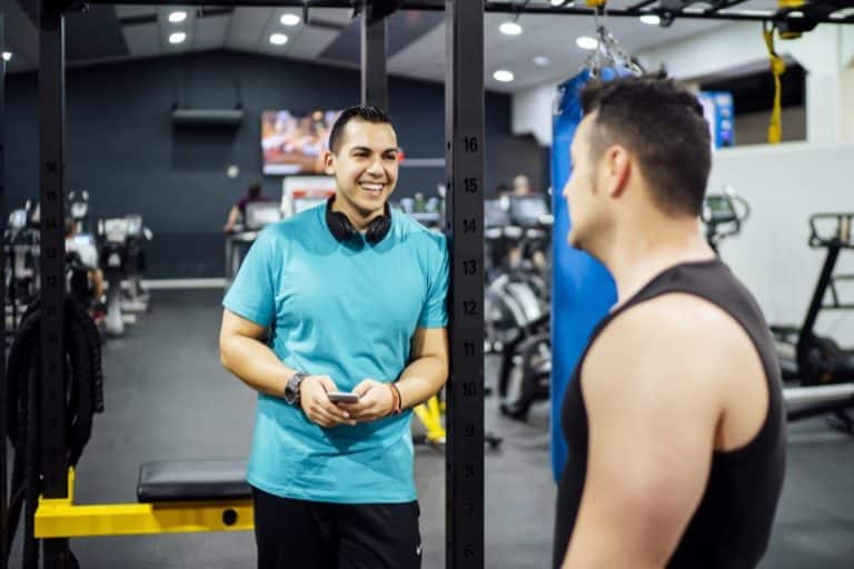 Two men training in gym looking at mobile phone