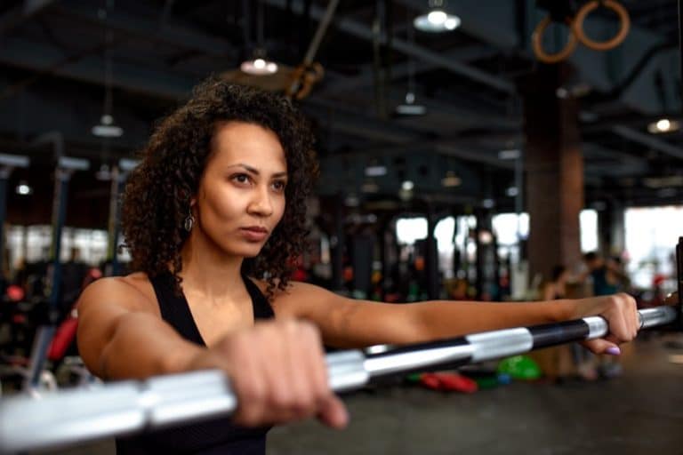 Portrait of young african american woman lifting barbell while exercising in crossfit gym. Self-motivation, keep the body in good shape, athletic endurance, heavy weight training