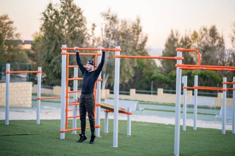 Young Hispanic man doing his workout in the morning exercising on a horizontal bar