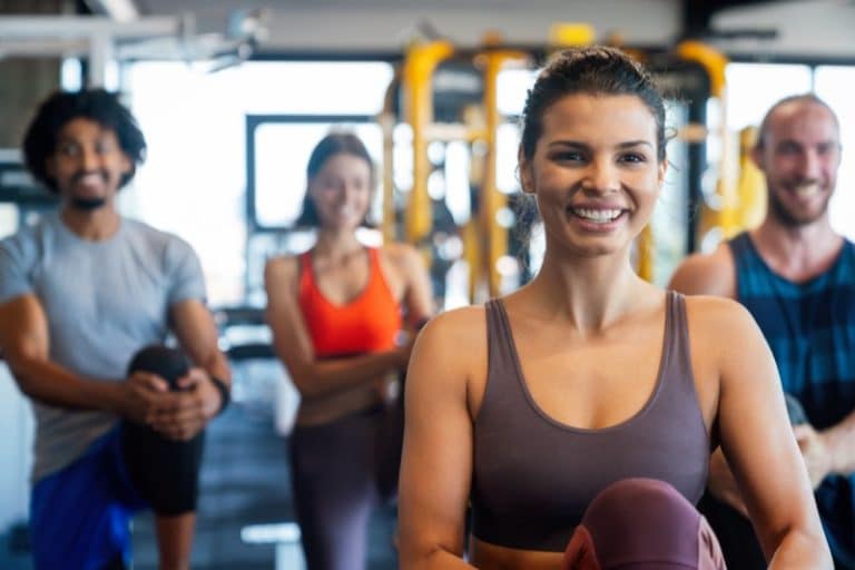 Group of happy people friends working out in gym together