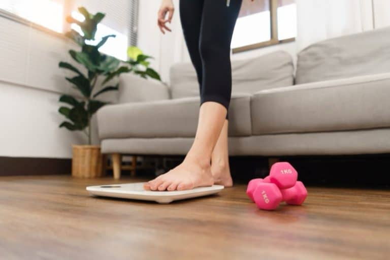 Healthy and weight loss concept, Young Asian woman stepping on weighing scales after weight control